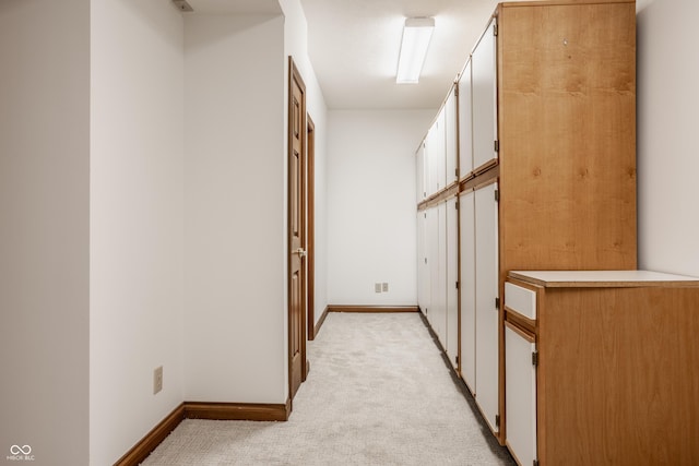 corridor featuring baseboards and light carpet