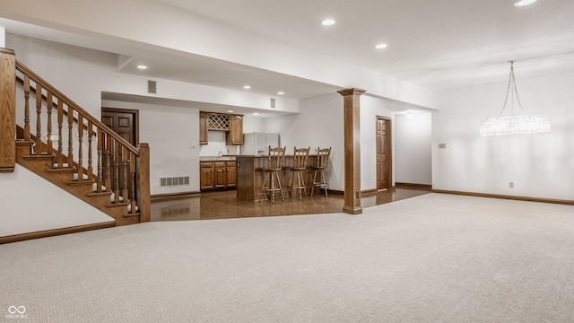 unfurnished living room with visible vents, dark carpet, recessed lighting, indoor wet bar, and stairs