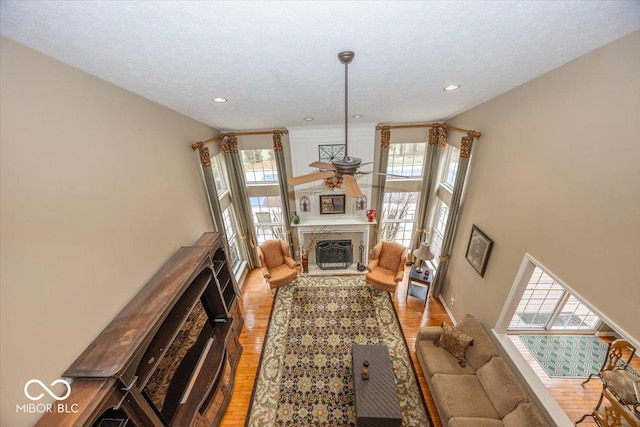 living room featuring light hardwood / wood-style flooring, a premium fireplace, and a textured ceiling