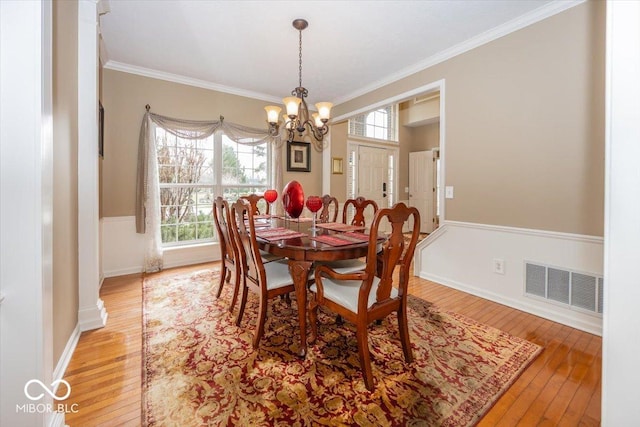 dining area featuring crown molding, a notable chandelier, and hardwood / wood-style flooring