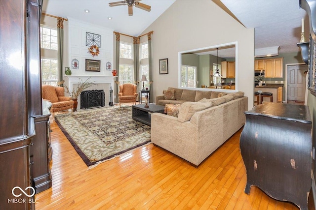 living room featuring high vaulted ceiling, light hardwood / wood-style floors, and ceiling fan