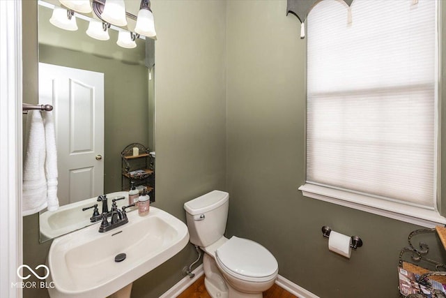 bathroom featuring an inviting chandelier, sink, and toilet