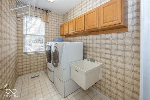 clothes washing area featuring cabinets, sink, and washing machine and dryer