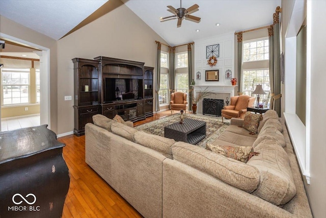 living room with hardwood / wood-style flooring, ceiling fan, and high vaulted ceiling