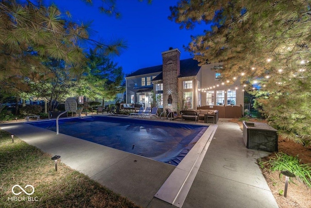 pool at night featuring an outdoor hangout area and a patio