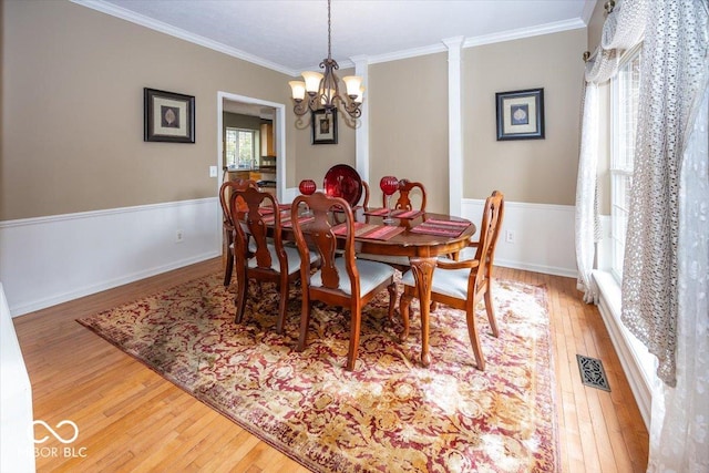 dining space with hardwood / wood-style flooring, crown molding, and a notable chandelier