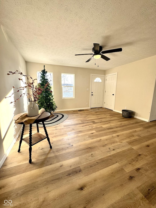 foyer with wood-type flooring, a textured ceiling, and ceiling fan