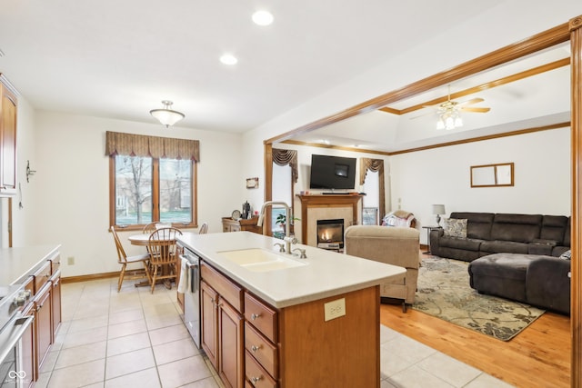 kitchen featuring a tile fireplace, sink, ceiling fan, an island with sink, and stainless steel appliances