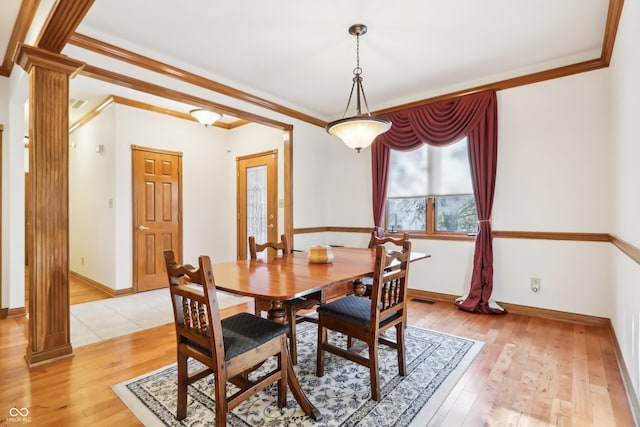 dining space with ornate columns, light wood-type flooring, and ornamental molding