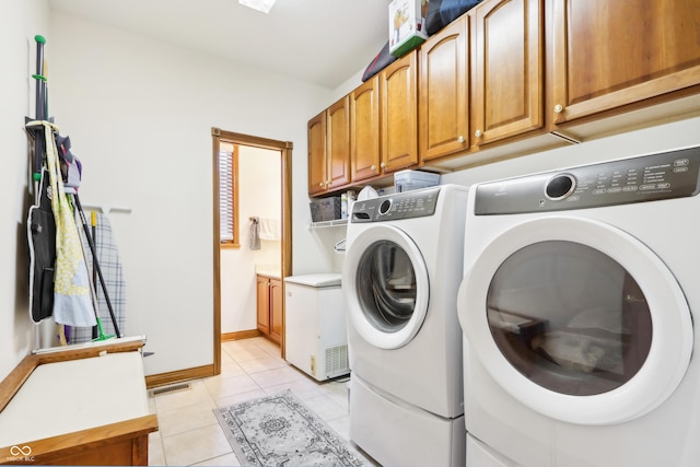 laundry room with cabinets, light tile patterned floors, and washing machine and dryer