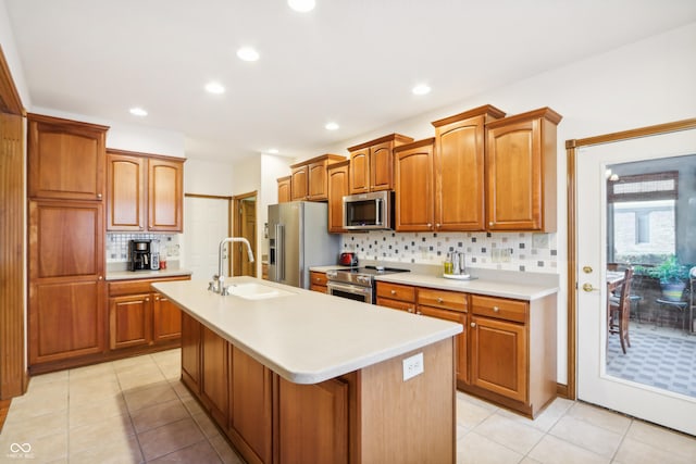 kitchen featuring backsplash, sink, a kitchen island with sink, and appliances with stainless steel finishes