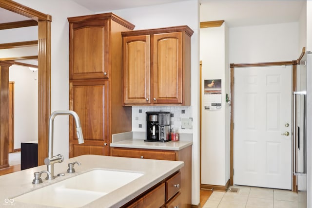 kitchen featuring decorative backsplash, light tile patterned floors, and sink