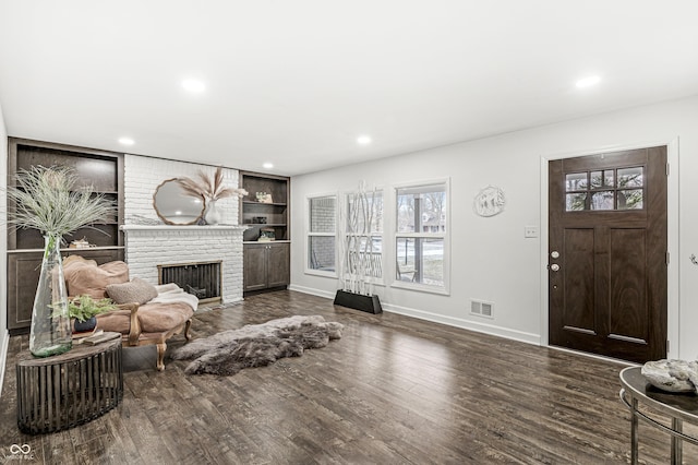 living room featuring dark wood-type flooring and a brick fireplace