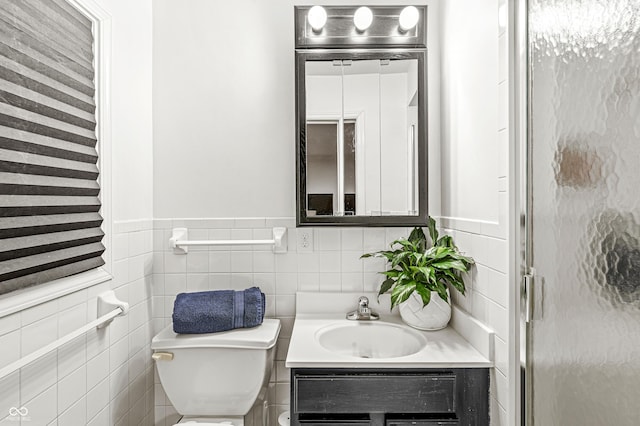 bathroom with vanity, toilet, tile walls, and walk in shower