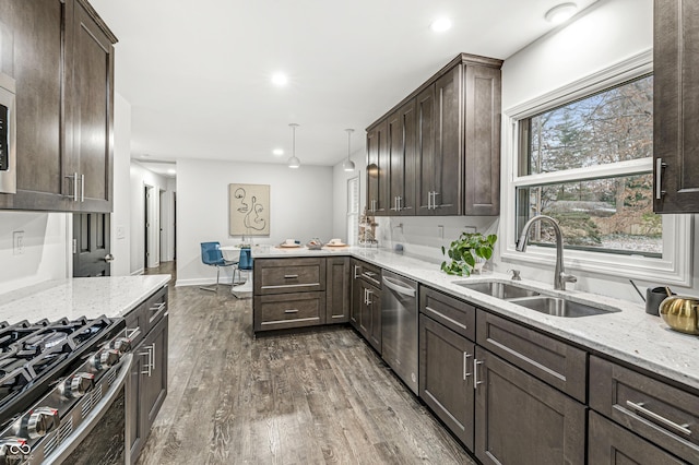 kitchen featuring sink, dark wood-type flooring, stainless steel appliances, kitchen peninsula, and pendant lighting