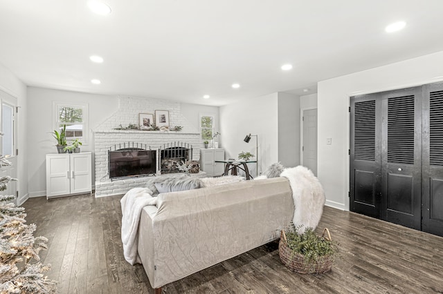 living room featuring dark hardwood / wood-style flooring and a brick fireplace