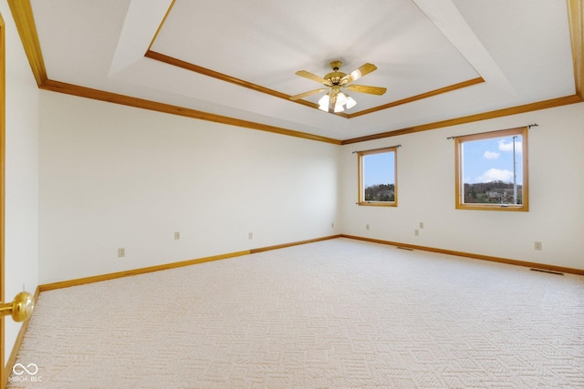 unfurnished room with a raised ceiling, ceiling fan, and light carpet