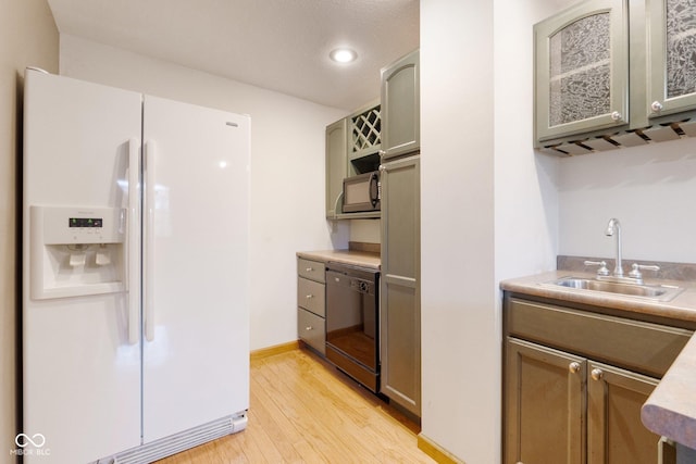 kitchen featuring dishwasher, light hardwood / wood-style floors, white fridge with ice dispenser, and sink