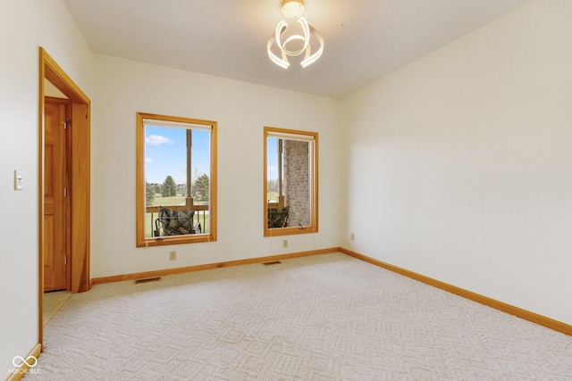 unfurnished room featuring light colored carpet and a chandelier