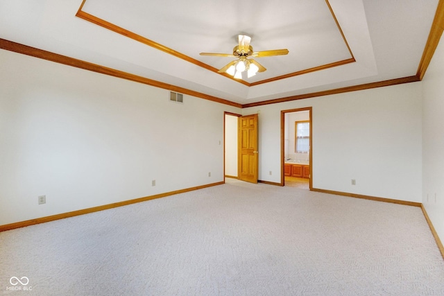 carpeted empty room featuring ceiling fan, crown molding, and a tray ceiling