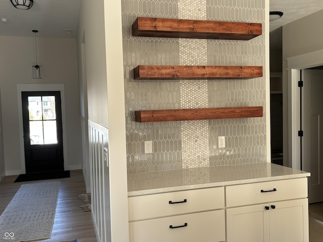 kitchen with tasteful backsplash, decorative light fixtures, dark hardwood / wood-style flooring, and white cabinets