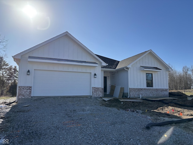 view of front of home featuring driveway, brick siding, and board and batten siding