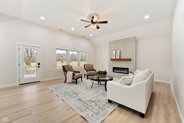 living room featuring a large fireplace, light wood finished floors, baseboards, and recessed lighting