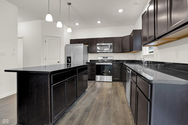 kitchen featuring stainless steel appliances, sink, decorative light fixtures, dark hardwood / wood-style floors, and a kitchen island