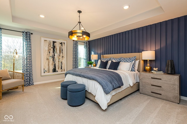 bedroom with carpet flooring, a tray ceiling, and an inviting chandelier