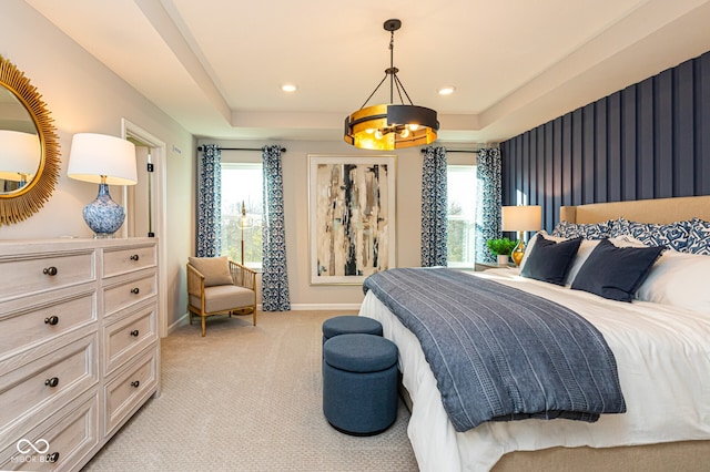 carpeted bedroom with a raised ceiling, multiple windows, and a chandelier