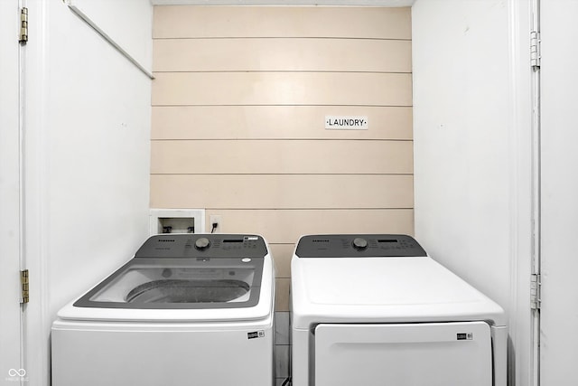 laundry area with separate washer and dryer and wooden walls