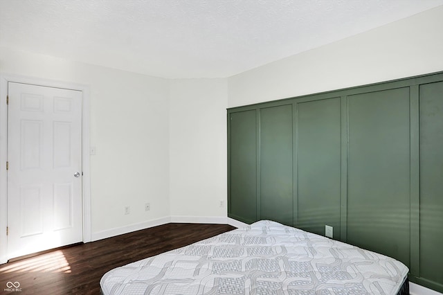 bedroom featuring a textured ceiling, dark wood-type flooring, and a closet