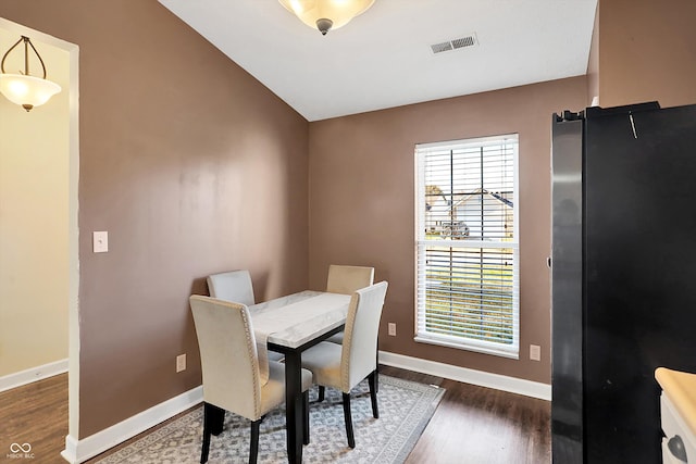 dining area featuring vaulted ceiling and dark wood-type flooring