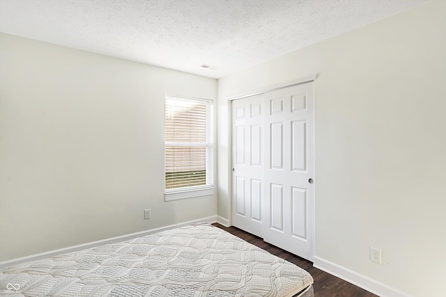 bedroom featuring hardwood / wood-style floors, a textured ceiling, and a closet