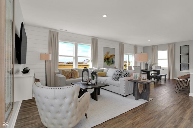 living room featuring a wealth of natural light, wooden walls, and hardwood / wood-style flooring