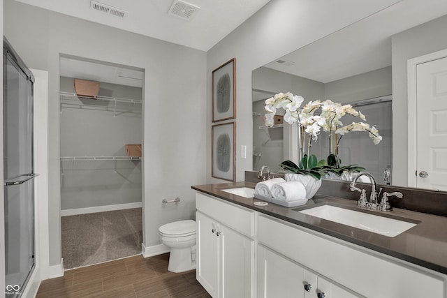 bathroom with hardwood / wood-style floors, vanity, toilet, and walk in shower