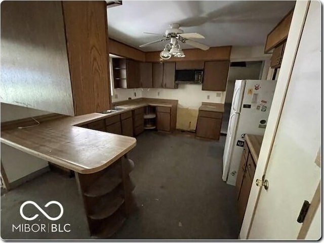 kitchen featuring a breakfast bar area, kitchen peninsula, ceiling fan, and white refrigerator