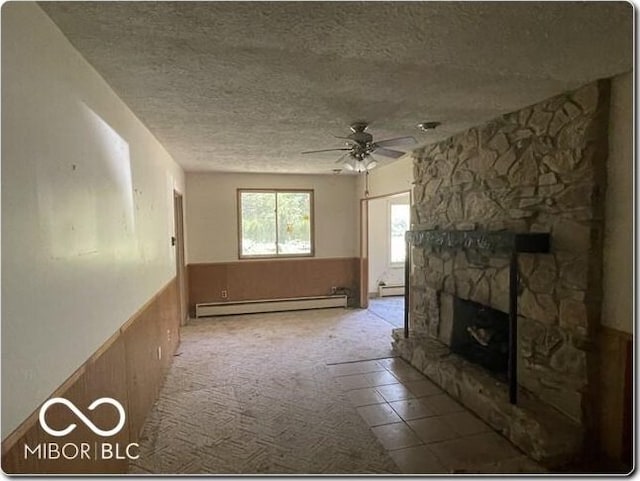 unfurnished living room featuring a baseboard heating unit, a stone fireplace, carpet flooring, ceiling fan, and a textured ceiling