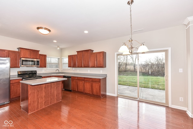 kitchen with hanging light fixtures, stainless steel appliances, dark hardwood / wood-style flooring, a notable chandelier, and a kitchen island