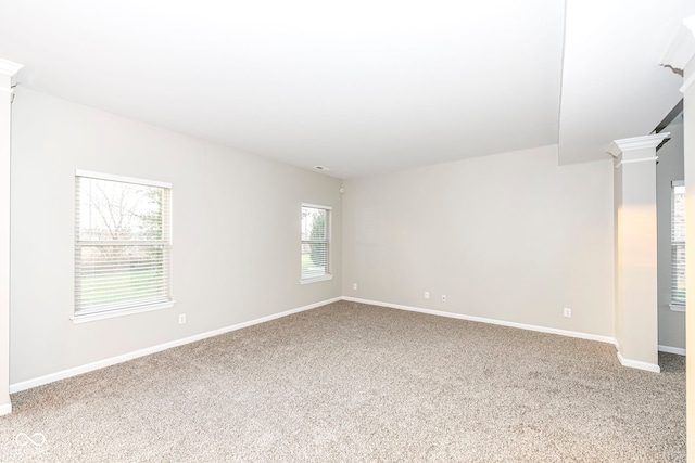 empty room with a healthy amount of sunlight, carpet floors, and ornate columns