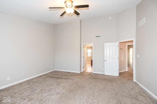 unfurnished bedroom featuring carpet flooring, ceiling fan, and a high ceiling