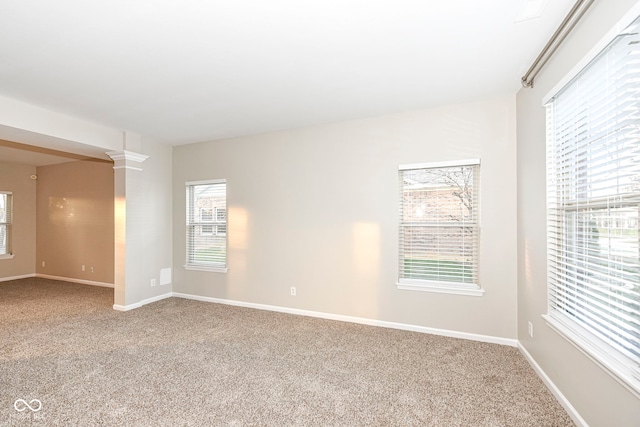 spare room with decorative columns and carpet