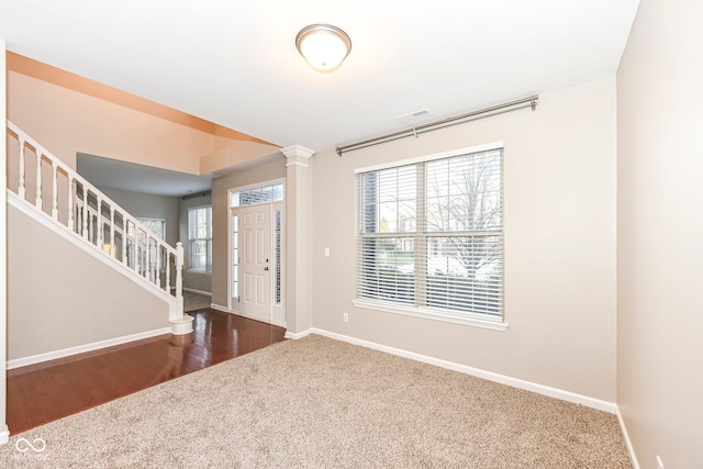 entrance foyer featuring dark wood-type flooring, a wealth of natural light, and decorative columns