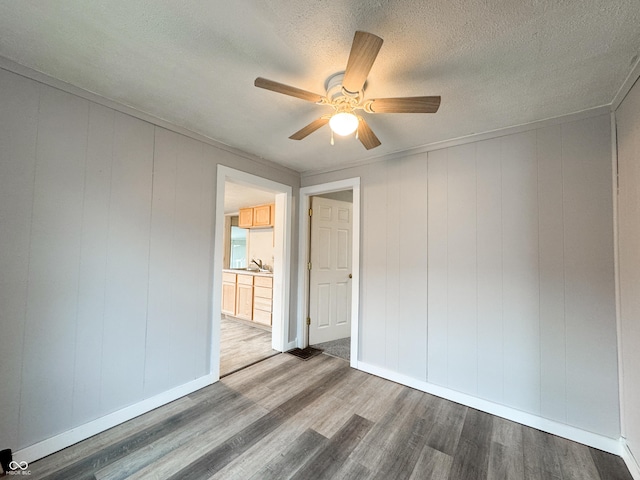 empty room featuring hardwood / wood-style flooring, ceiling fan, wood walls, and a textured ceiling