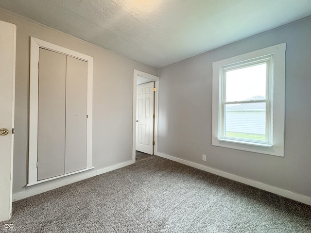 unfurnished bedroom featuring carpet flooring, a textured ceiling, and a closet