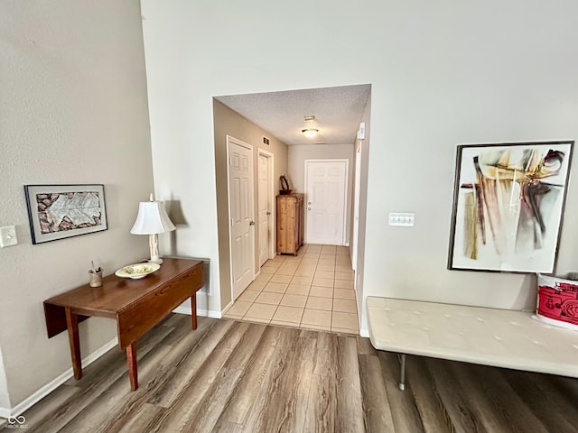 hallway featuring a textured ceiling and light hardwood / wood-style flooring