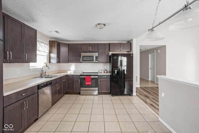 kitchen with a textured ceiling, sink, stainless steel appliances, and decorative light fixtures