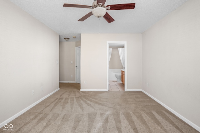 unfurnished bedroom with ceiling fan, light colored carpet, a textured ceiling, and connected bathroom