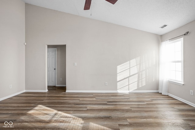 spare room featuring hardwood / wood-style floors, a textured ceiling, and high vaulted ceiling