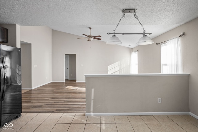 empty room featuring a textured ceiling, ceiling fan, light hardwood / wood-style floors, and vaulted ceiling